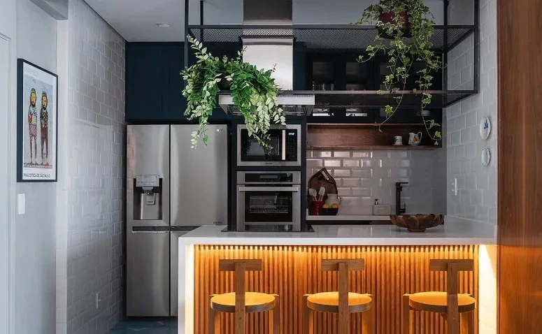 Cozinha moderna com ilha, bancada iluminada e três banquetas